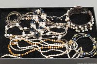 Overall shot of multiple jewelry pieces including necklaces and bracelets featuring freshwater pearls, silver, tiger's eye, and a gold filled piece.