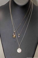 Front view of three sterling silver chains displayed on black bust, showing pendants and varying chain styles and lengths.