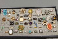 Grouped shot showing over 50 assorted costume rings in a display tray with a variety of styles and colors.