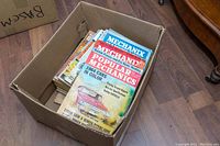 View of the open box showing stacked magazines with visible Popular Mechanics and Mechanix titles.