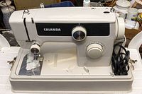 Front angled view of the CALANDA sewing machine showing the body, dials, and thread placement area.
