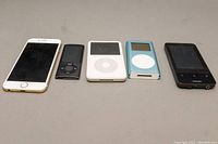 Front view of iPhone, three iPods, and Philips MP3 player showing screen condition and form factor.