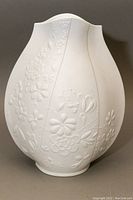 Front angle of the white bisque porcelain vase showing floral embossed detail and bulbous shape.