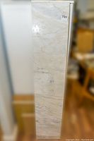 Vertical view of one long marble tile plank showing natural veining and smooth polished surface.