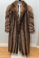 Front view of the full-length raccoon fur coat on a mannequin showing the coat's length, fur texture, and open front.
