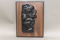 Full frontal view of black obsidian stone carving mounted on rectangular wood plaque.