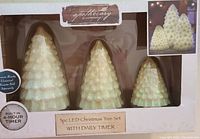 Front view of the boxed 3-piece LED Christmas Tree candle set showing three white glittery tree-shaped candles with timer feature.