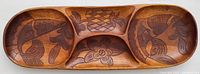 Full top view of the wooden serving tray featuring three carved sections with fish and pineapple motifs.