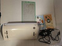 Cricut Personal Electronic Cutter machine, power adapter, cutting mat, and two cartridges shown on a flat surface.
