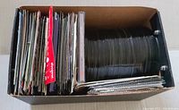 Box filled with numerous loose CD discs and numerous inserts, evidence of a large variety of music CDs.