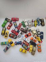 Overview of the 40 vintage toy cars in assorted colors and types arranged on a white surface.