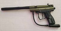 Side view of Spyder Victor paintball marker showing the olive green metal body with black barrel and grip, and Spyder Victor branding.