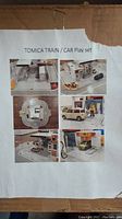 Photo of the original box label showing images of the assembled Tomica Train/Car Play set and gas station playset components.