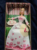 Barbie doll in Victorian-style white dress with pink floral accents, including hat and tea set inside box.