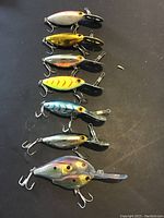Seven assorted LIVETARGET fishing lures displayed including various colors such as silver, gold, yellow with red stripes, blue stripes, and multi-color, each equipped with treble hooks and diving lips.