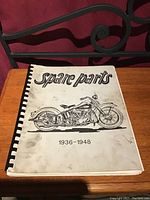 Front cover of the coil bound spare parts catalogue featuring an illustration of a vintage Harley Davidson motorcycle and the title 'spare parts 1936-1948'.