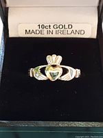 Front view of ring in original box showing Claddagh design and green heart-shaped stone