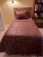 Twin wicker bed with patterned comforter and pillow, showing headboard and mattress setup.