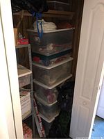 Stacked plastic bins containing assorted Christmas decorations inside a closet.