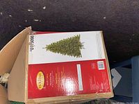 Boxed 6.5 ft artificial Christmas tree from Holiday Living brand packed in red and white box.