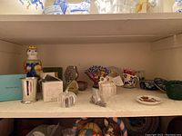 Shelf with assorted collectible items including ceramic figurines, crystal pumpkins, and pottery pieces