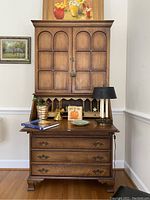 Front view of the closed wooden secretary desk with decorative items on desk surface.