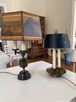 Two brass library lamps on a table showing the difference in size and shade style