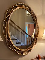 Full view of the oval gold framed mirror mounted on wall, showing interior background reflection