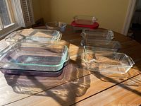 Photo of the entire set of 11 Pyrex glass bakeware dishes of various sizes and shapes on wooden table