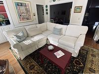 Front left view of cream sectional sofa in living room showing rolled arms and slipcover.