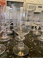 Close-up of one tall tulip style stemware glass showing the flared rim, rounded stem, and clear glass material.