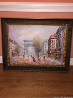 Full front view of the framed village square painting showing the arch and buildings.