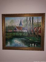 Front view of framed oil painting showing a landscape with a stream, village, and church steeple.