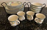 Eight dinner plates stacked, six salad plates stacked, four cereal bowls stacked and four mugs arranged front