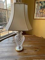 Photo of Waterford crystal table lamp on wooden table, showing diamond-patterned crystal base, brass base, and cream fabric lampshade