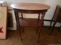 Front and side view of 2-tier wooden accent table showing serpentine twisted legs and claw foot bases, with minor surface wear.