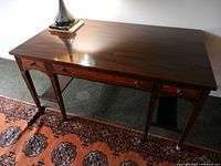 View of wooden desk top and front drawers, showing polished finish and drawer handles