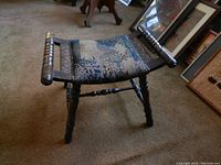 Side angle view of foot stool showing turned legs and blue patterned upholstered top