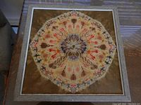 Full frontal view of the framed batik fabric art showing the entire square piece with brown background and floral design.