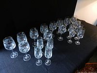 Photo showing the entire set of 12 wine glasses and 8 champagne flutes arranged on a black surface.