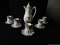 Full set of Imperial German porcelain teapot with five matching teacups and saucers on dark background
