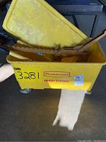 Yellow Rubbermaid bucket labeled 'Finish System' containing metal tools