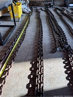 Photo showing the full length of the heavy steel chain lying on a concrete floor with measurement tape stretched alongside, indicating length at 34 feet.