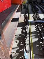 Photo showing long heavy-duty metal chain laid out on the floor with measuring tape indicating approximately 17 feet length.