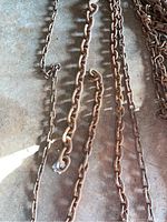 Close-up of five metal chains showing varied link sizes and rusted condition.