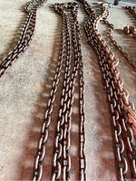 Photo showing both long rusted metal chains laid out on a concrete floor, each about 14 feet long.