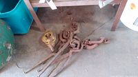Five come along hand winches arranged on a garage floor showing metal hooks and handles