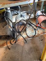 Photo showing three propane heaters with cords on a metal cart, dusty and rusty.