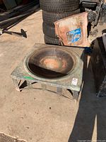 Overall angled view showing the top and side of the metal fire pit with decorative embossing and rust.