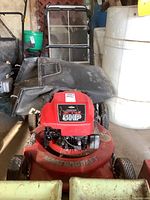 Front view of red Mastercraft lawn mower with two black catcher bags attached at the back, showing overall structure and wheels.